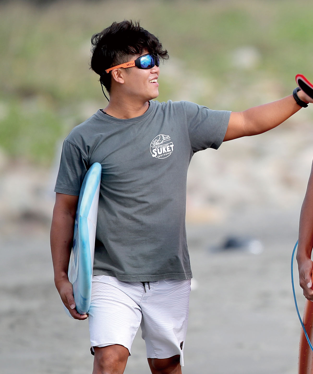 男性配戴FENIX系列水上運動太陽眼鏡拿藍色衝浪板